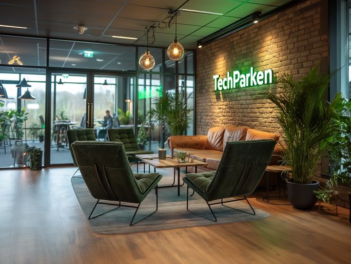 TechParkens lounge med grønne lænestole og logo på murstensvæg